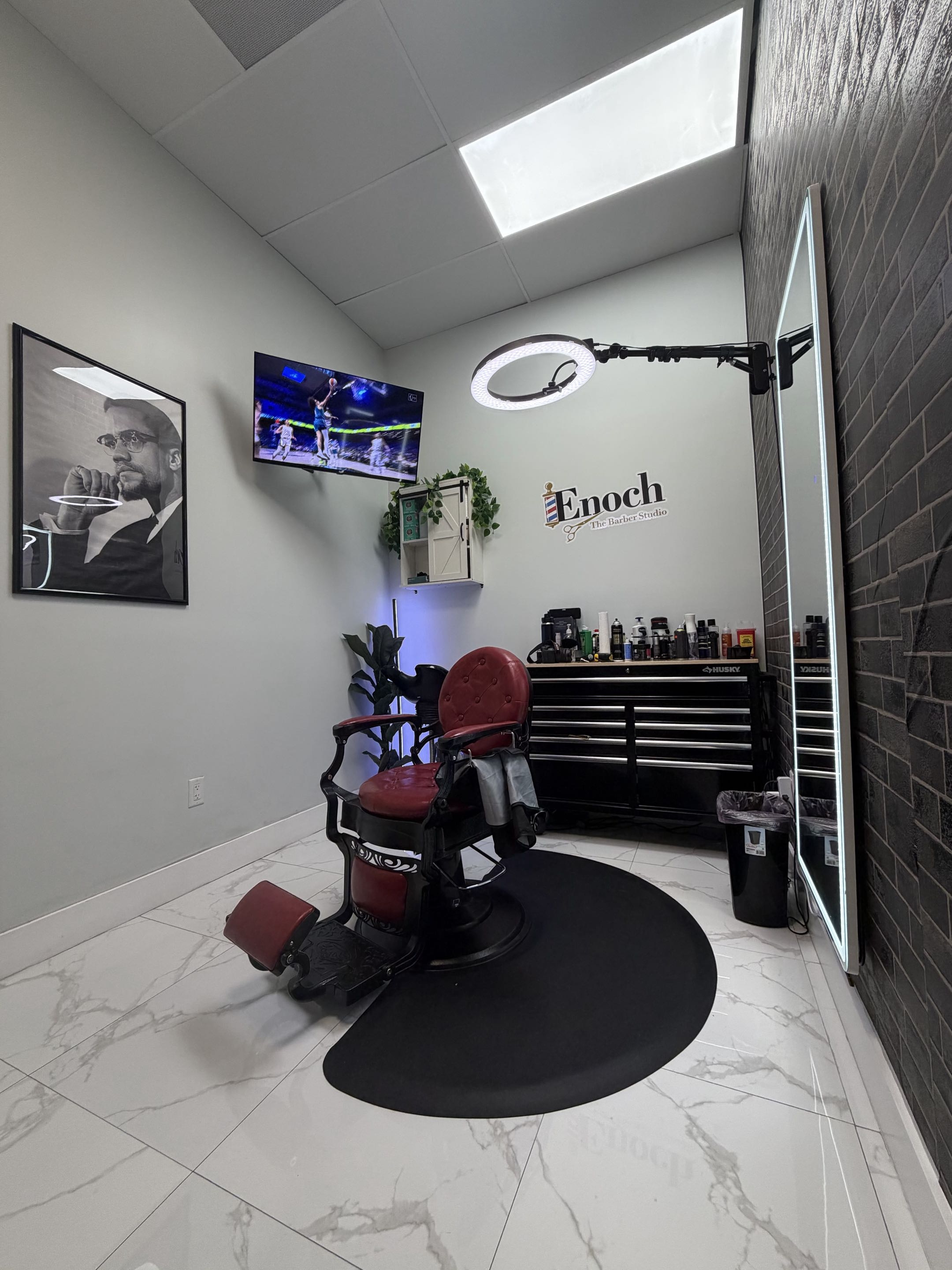 Full view of Enoch The Barber Studio — private space with red barber chair and brand logo on wall